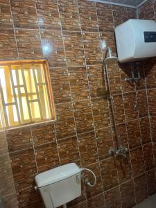 een badkamer met toilet en raam in een betegelde muur bij Otam Homes in Ondo +1 foto