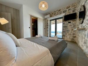 a bedroom with a large bed and a stone wall at Ocean Bliss Villa, By Hellocrete in Kerames