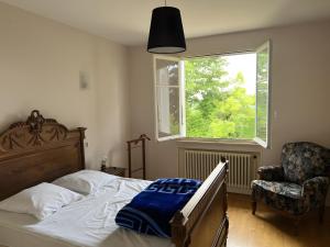 a bedroom with a bed and a chair and a window at Adélaide Cottage in Chevagny-les-Chevrières