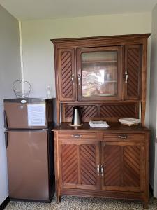 a large wooden entertainment center next to a refrigerator at Adélaide Cottage in Chevagny-les-Chevrières