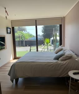 une chambre avec un grand lit et une grande fenêtre dans l'établissement Casa amplia y moderna en Cerro Tacna, Maitencillo, à Maitencillo