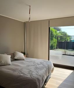 une chambre avec un lit et une grande fenêtre dans l'établissement Casa amplia y moderna en Cerro Tacna, Maitencillo, à Maitencillo