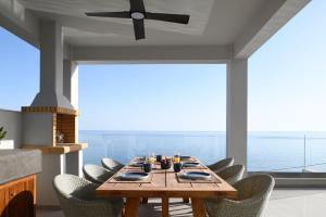 een eetkamer met een tafel en stoelen en een plafondventilator bij Rozites Luxury Beachfront Villa, By Hellocrete in Kerames