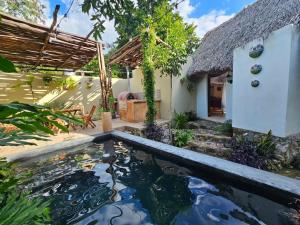 a koi pond in front of a house at Cabañas Los Gallitos Ecolodge in Sacalum