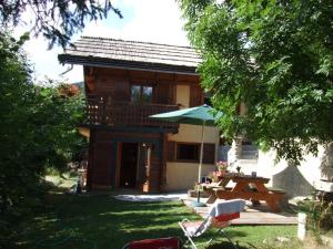 a house with a table and a chair and an umbrella at Confortable 2 pièces avec WiFi et parking privé à Saint-Chaffrey - FR-1-762-14 in Saint-Chaffrey