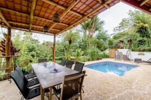 Un patio con mesa y sillas y una piscina. en Paradiselodge - Poolvilla, en Platanillo
