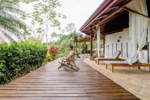 una terraza de madera con sillas y una casa en Paradiselodge - Poolvilla, en Platanillo