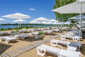 a bunch of white chairs and umbrellas on a beach at Hotel Warszawianka in Jachranka