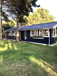 une maison noire avec une cour devant dans l'établissement Cozy cottage near beach and nature, à Martofte