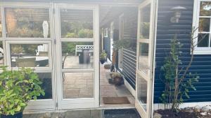 une terrasse couverte d'une maison avec des fenêtres et des plantes dans l'établissement Cozy cottage near beach and nature, à Martofte 20 autres photos