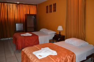 a hotel room with two beds with towels on them at Hostal Bona Nit in Trujillo