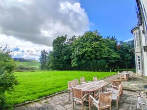a patio with a table and chairs and a field at Hillside House in Saline