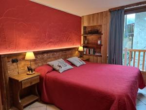 a bedroom with a red bed with a red wall at L'Abreny in Brusson