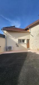 a white building with a door and a driveway at la petite écurie in Soleymieu