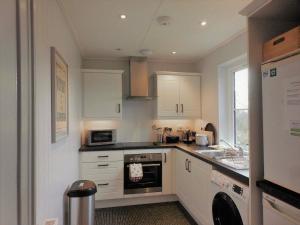a kitchen with white cabinets and a stove top oven at Ardshiel in Foyers