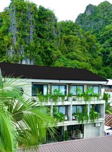an exterior view of a hotel with a mountain in the background at Z Garden Hotel Managed by H Hospitality in El Nido
