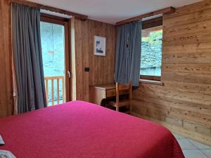 a bedroom with a bed and a desk and a window at L'Abreny in Brusson
