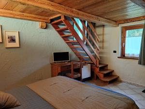 a bedroom with a bed and a desk with a computer at L'Abreny in Brusson