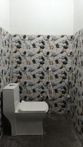 a bathroom with a toilet and a wallpaper with eyes at Rumba Homestay in Darjeeling