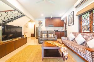 a living room with a couch and a tv at Cabatales - 3BHK Villa Near Candolim Beach in Candolim