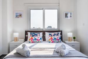 a bedroom with a bed with pillows and two windows at Sonic 2-Bedroom Apartment in Larnaca +10 photos