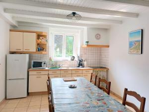 a kitchen with a table and a white refrigerator at Chambre kerantum in Mahalon