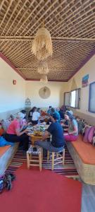 een groep mensen die aan een tafel in een kamer zitten bij Dar Bani in Zagora