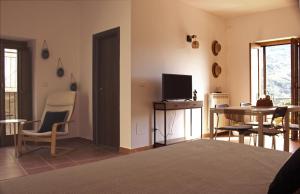 a living room with a bed and a desk with a television at Lumira Vista – Panorama in Sangineto