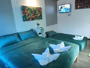 two beds with white flowers on them in a room at อู่ตะเภาโฮมสเตย์byต้นไทร in Ban Nong Sa