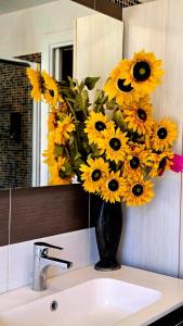 a vase filled with yellow flowers on top of a sink at Nizzeti Home Catania Sicily Sea View in Aci Catena