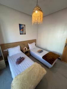 a room with two beds and a chandelier at Atlantic view Tamraght 1 in Tamraght Oufella