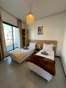a bedroom with two beds and a chandelier at Atlantic view Tamraght 1 in Tamraght Oufella