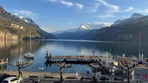 a dock in the middle of a lake with mountains at Erholung am Vierwaldstättersee, komfortables 3-Bett-Zimmer in Brunnen in Brunnen