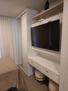 a bedroom with a flat screen tv on a wall at Loft av central in Xangri-lá