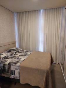 a bedroom with a bed and a window with curtains at Loft av central in Xangri-lá