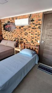 a bedroom with a bed and a brick wall at Garagem 36 próximo a Serra do Rio do Rastro in Louro Müller