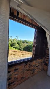 a window in a room with a brick wall at Garagem 36 próximo a Serra do Rio do Rastro in Louro Müller