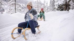 una mujer sentada en un trineo en la nieve en Pension Wald, en Faistenau