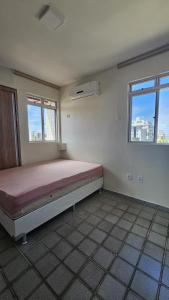 a bedroom with a bed in a room with two windows at Refúgio próximo ao mar in Cabedelo