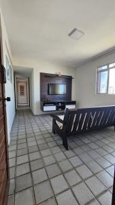 a living room with a bench and a tv at Refúgio próximo ao mar in Cabedelo