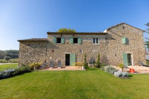 a large stone house with a grass yard at Terres Élaïs in Robion en Luberon