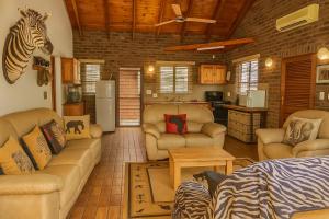 a living room with furniture and a zebra head on the wall at Tree Lodge by My Adventure House in Marloth Park