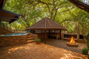 a gazebo with a fire pit in a yard at Tree Lodge by My Adventure House in Marloth Park +9 photos