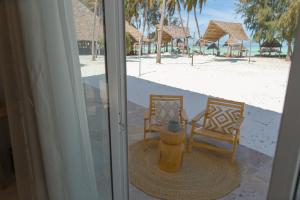 zwei Stühle und ein Hydrant an einem Strand in der Unterkunft Eco Mónica - By Cristal Resort in Paje + 33 Fotos