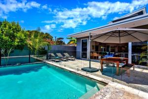 Una piscina con una sombrilla al lado de una casa. en Stonecutters 2, en Byron Bay