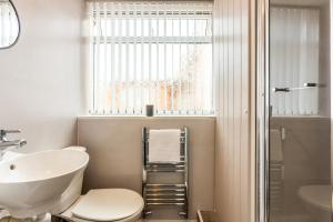 a bathroom with a sink and a toilet and a window at Sandhaven House in South Shields