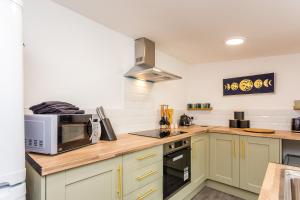 a kitchen with green cabinets and a microwave at Sandhaven House in South Shields +15 photos
