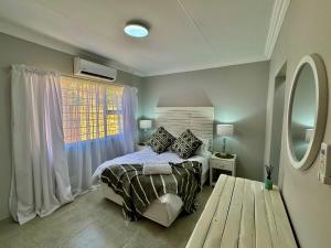 a bedroom with a bed and a window and a table at Urban Bliss Villa in Klerksdorp