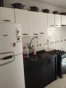 a kitchen with white cabinets and a white refrigerator at Casa de Temporada in Aracaju