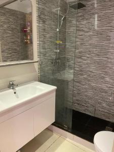 ein Badezimmer mit Waschbecken und Glasdusche in der Unterkunft Banana Village Surf Apartment in Aourir